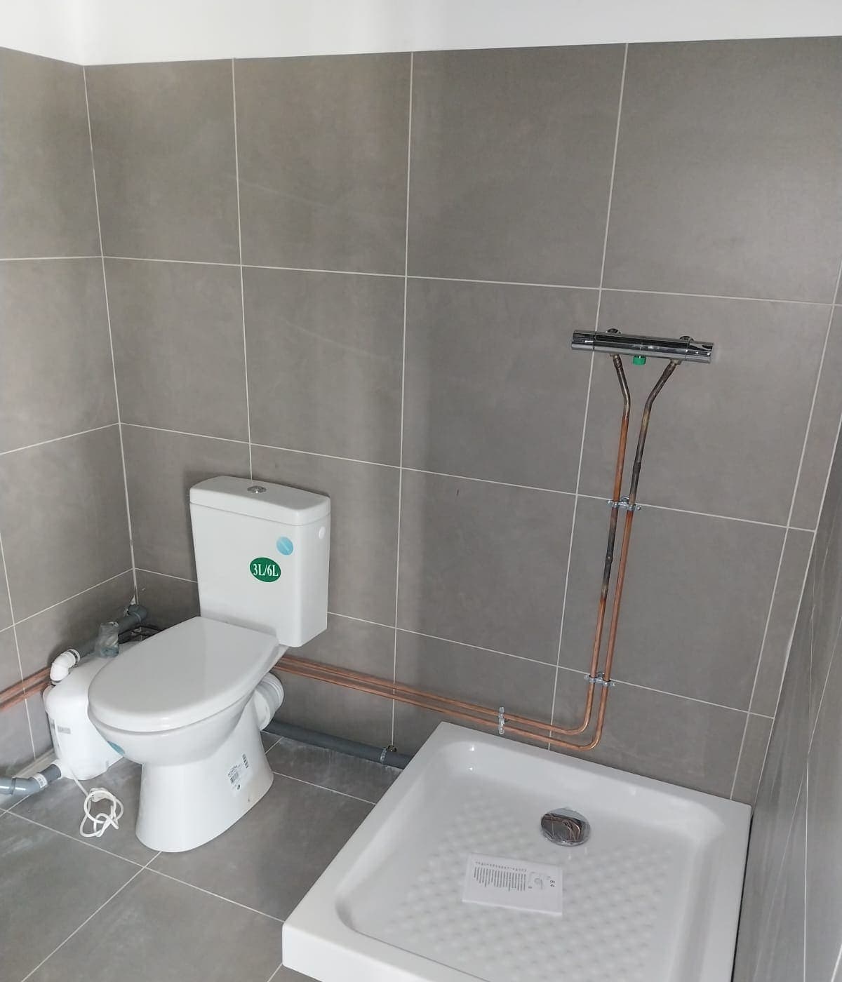 Salle d'eau avec WC, receveur de douche et alimentations en cuivre