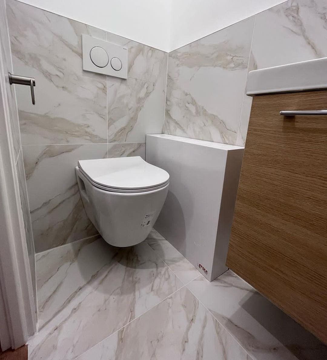 WC suspendu dans des toilettes carrelées avec meuble vasque en bois